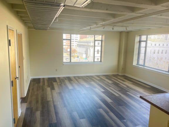 an empty room with hardwood floors and large windows