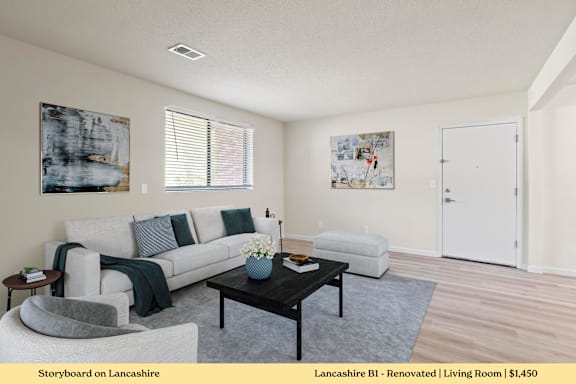 A living room with a grey couch, a coffee table, and two chairs.