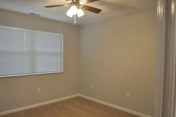 A room with a ceiling fan and a window with blinds.