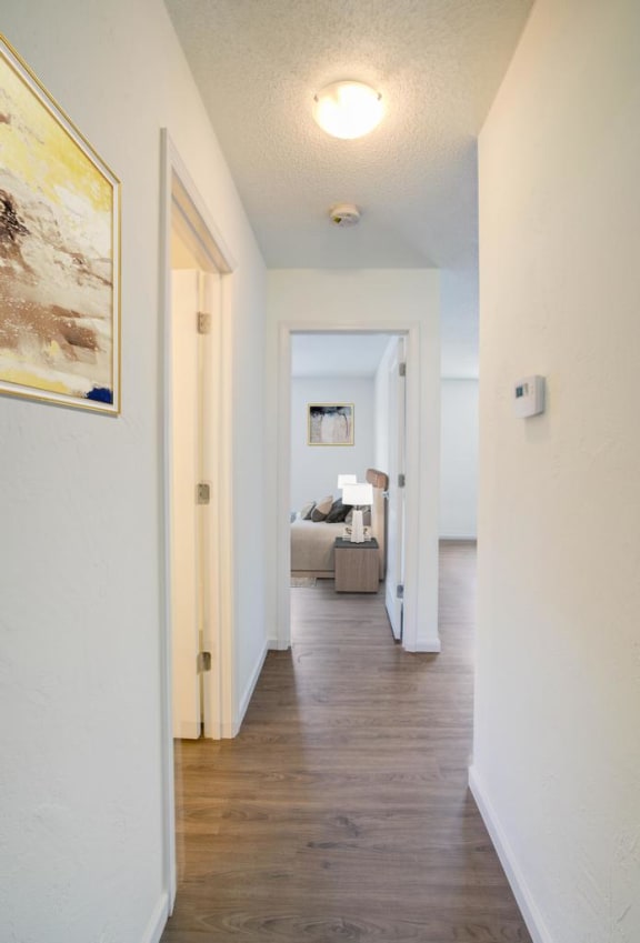 a hallway with white walls and a wooden floor