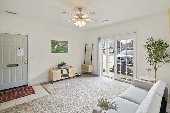 A living room with a white couch and a ceiling fan.