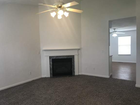 A room with a fireplace and a ceiling fan.
