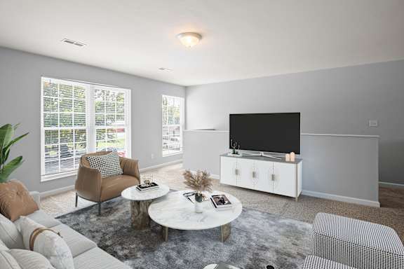 A living room with a white sofa, a coffee table, and a television.
