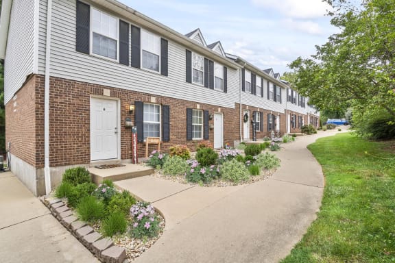 a row of townhomes with a sidewalk and flower beds in front of them