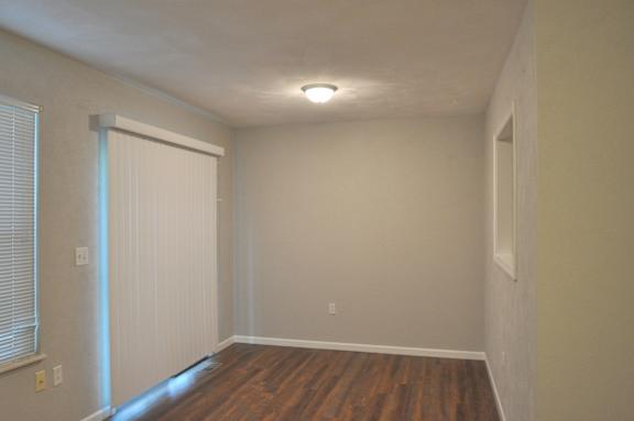 A room with a white door and wooden floor.