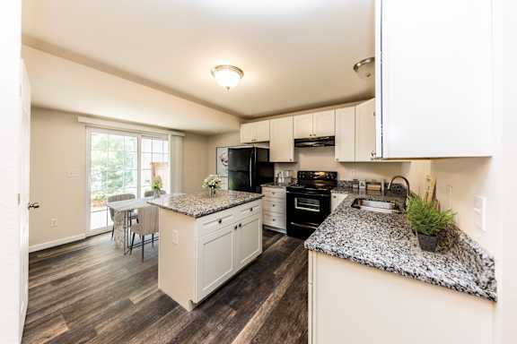 A kitchen with granite countertops and white cabinets.