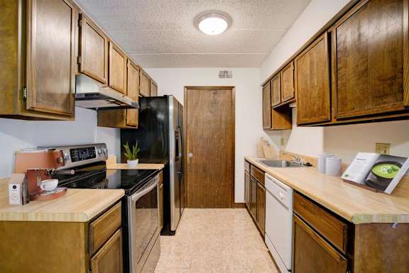 A kitchen with wooden cabinets and a black refrigerator.