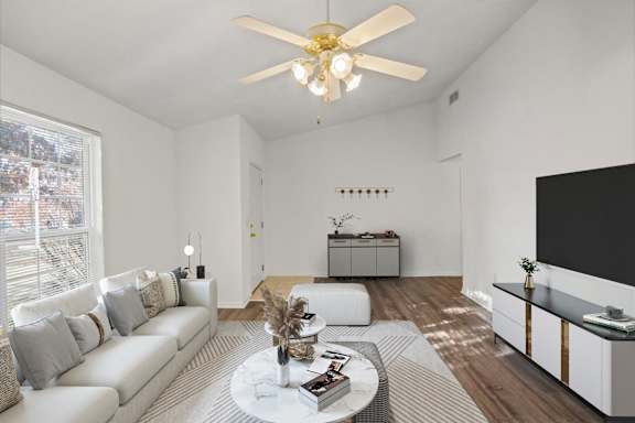 A living room with a white couch, a coffee table, and a ceiling fan.