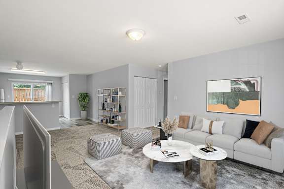 A living room with a grey couch, a coffee table, and a painting on the wall.