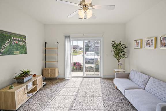 A living room with a grey couch, a wooden cabinet, a potted plant, and a framed picture on the wall.