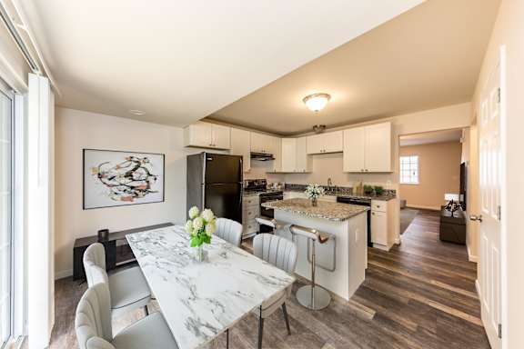 A kitchen with a marble table and chairs, a fridge, a sink, and a window.