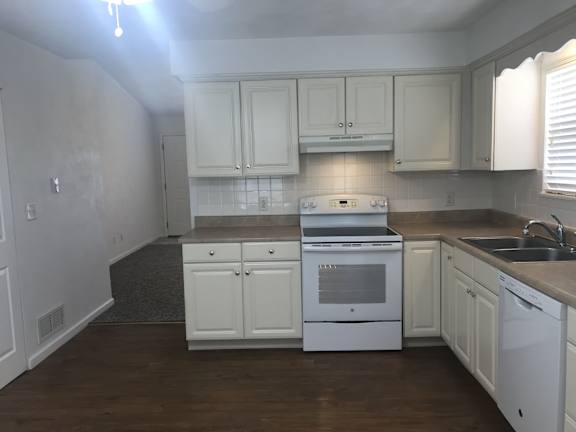 A kitchen with white cabinets and appliances.