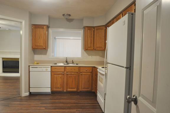 A kitchen with wooden cabinets and a white fridge.