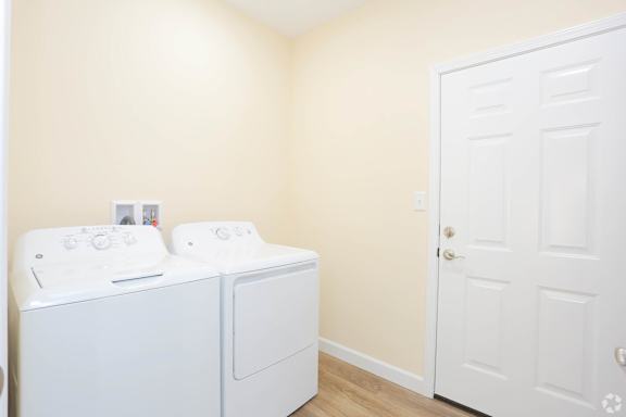 Two white washing machines in a laundry room.
