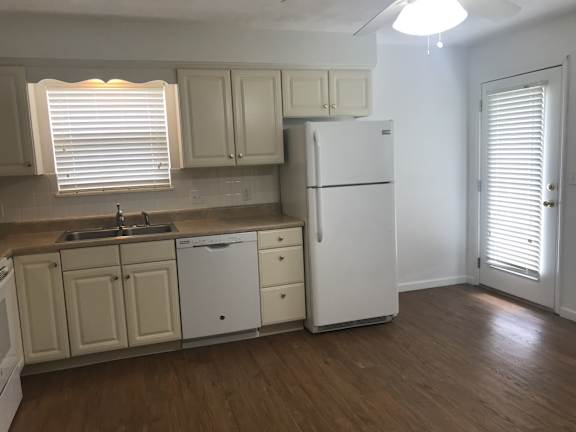 A kitchen with white appliances and wooden floors.