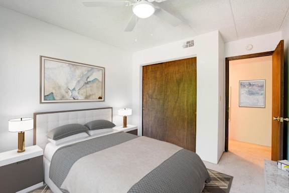A bedroom with a bed, two lamps, and a painting on the wall.