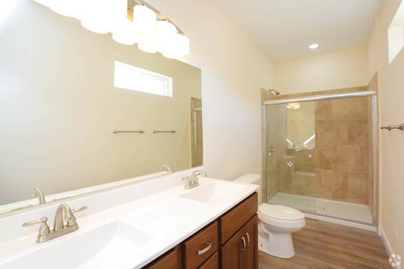 A bathroom with a white sink, toilet, and a glass shower stall.