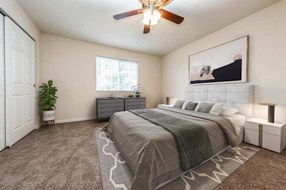 A bedroom with a bed, nightstands, and a ceiling fan.