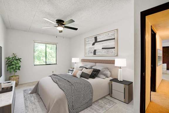 A bedroom with a bed, nightstand, and a ceiling fan.