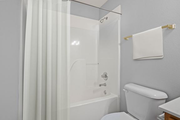 A white bathroom with a toilet, sink, and shower.