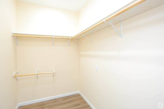 A room with a wall-mounted shelf and a wooden floor.