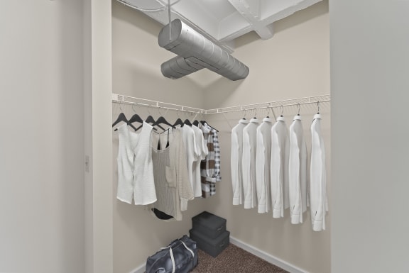 a closet with clothes hanging on a rack and a ceiling fan