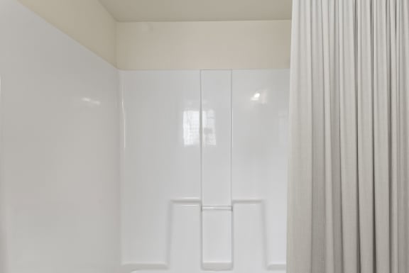 a bathroom with white walls and a shower curtain