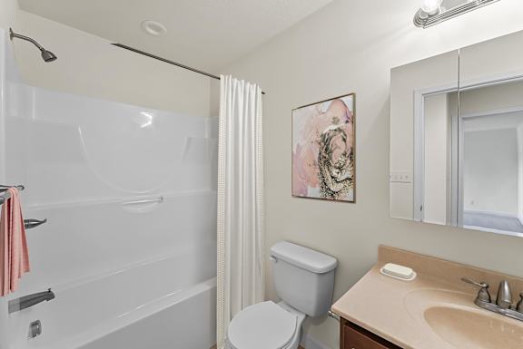 A bathroom with a toilet, sink, and shower.