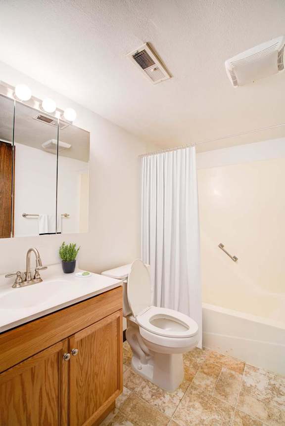 A white toilet in a bathroom with a sink and mirror.