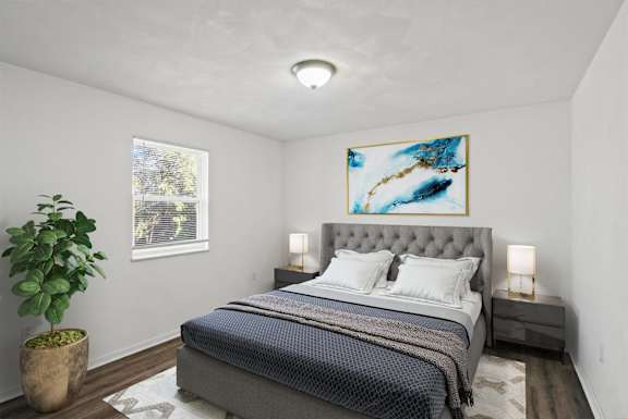 A bedroom with a bed, a potted plant, and a painting on the wall.
