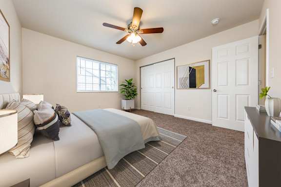 A bedroom with a bed, a ceiling fan, and a window.