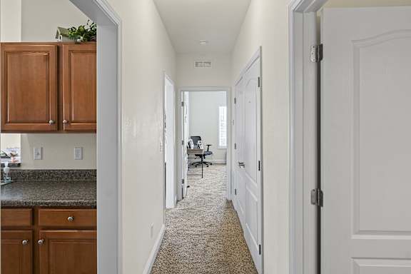 A hallway with a carpeted floor and white walls.