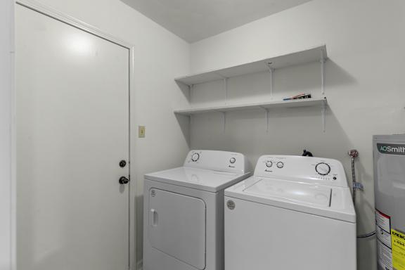 A white door is open to a laundry room with two washing machines.