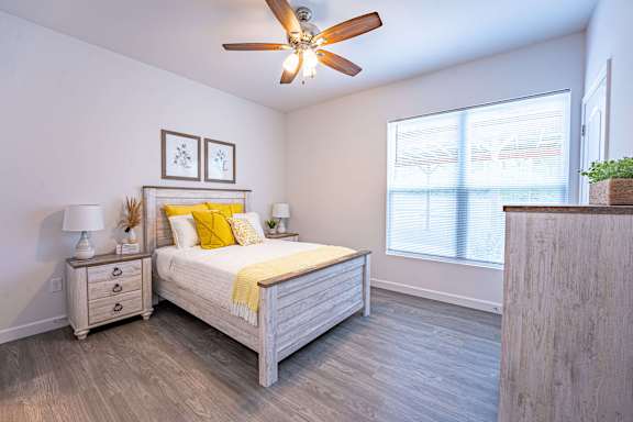 A bedroom with a bed, nightstands, and a ceiling fan.