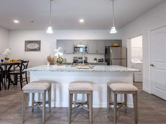 A kitchen with a bar and stools in the foreground.