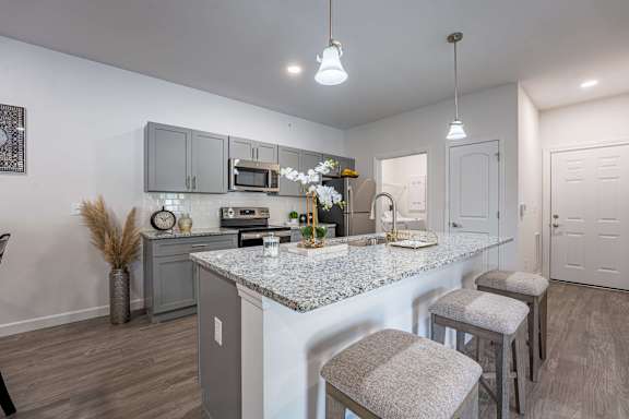 A kitchen with a granite countertop and grey bar stools.