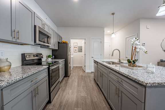 A kitchen with grey cabinets and a marble countertop.