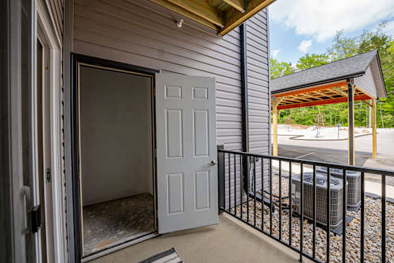A white door is open to a room with a black railing outside.