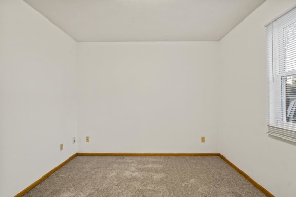 an empty room with a carpeted floor and a window