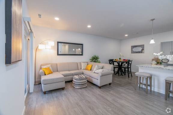 A modern living room with a grey sofa and a dining table.