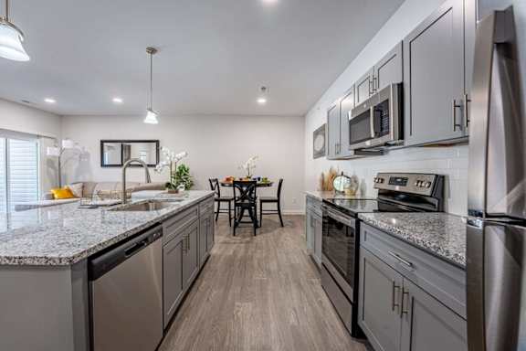 A modern kitchen with stainless steel appliances and a dining table set for four.