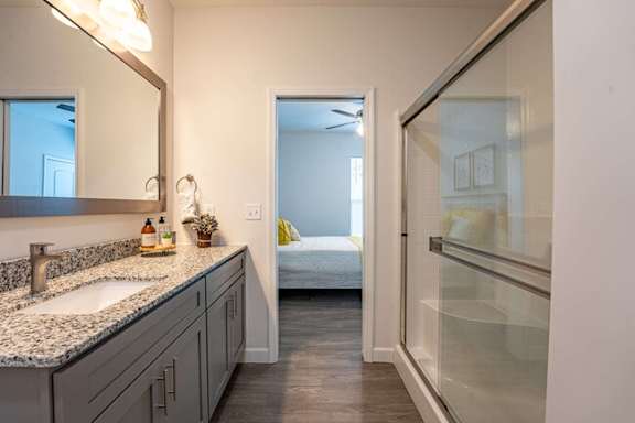 A bathroom with a sink, mirror, and a glass shower door.
