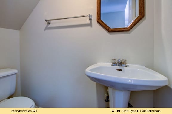 A white sink in a small bathroom with a toilet and a mirror.