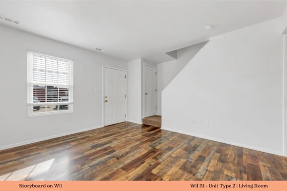 A living room with wooden flooring and white walls.