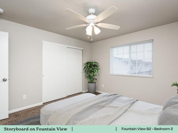 A bedroom with a bed, a ceiling fan, and a window.