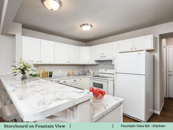 A kitchen with white cabinets and a marble countertop.