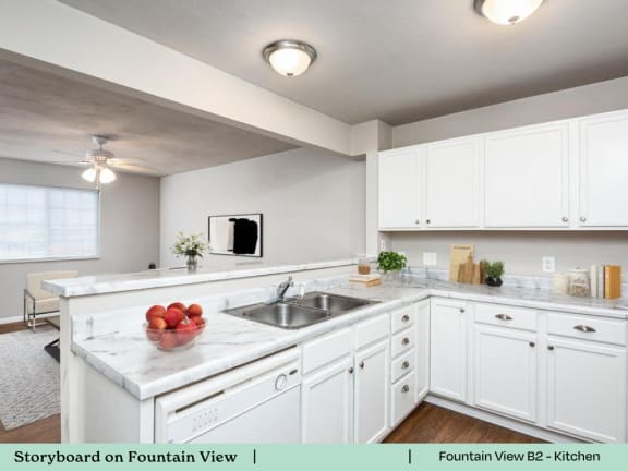 A kitchen with white cabinets and a marble countertop.