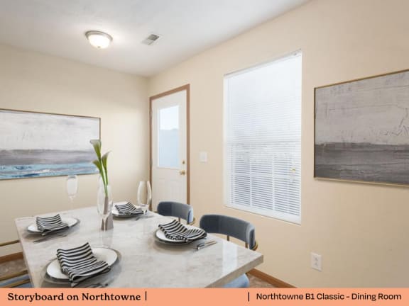 A dining room with a table set for two and a painting on the wall.