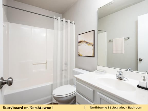 A white bathroom with a toilet, sink, and shower.