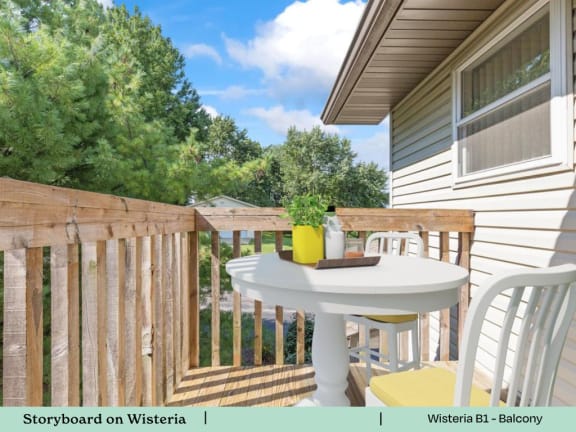 A balcony with a table and chairs overlooking a backyard.